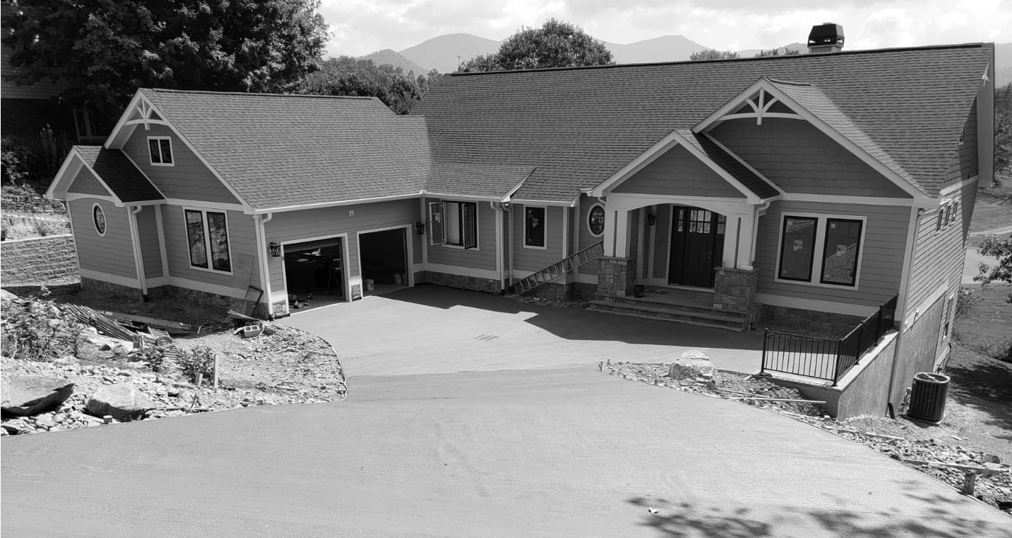 A black and white photo of a modern home with a two car garage and a concrete driveway